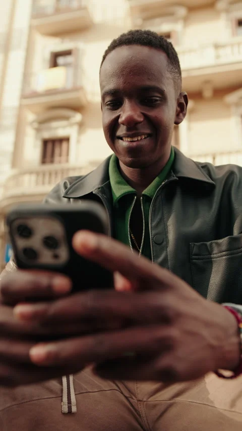 Vertical video, Young Man Smiles While Using Smartphone Outdoors Stock Footage 322126699