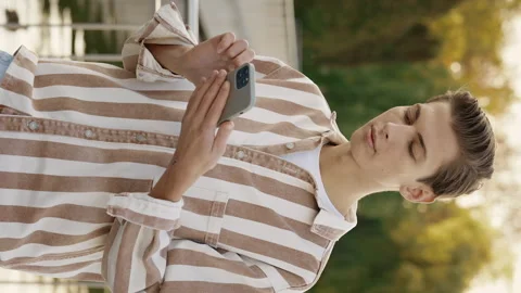 Vertical Video. Young Man Standing on the Street Using his Smartphone, Texting Stock Footage 240228799