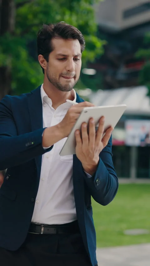 Vertical Video. Young Man Standing Outside and Using a Tablet and a Digital Pen 库存影片 306696113