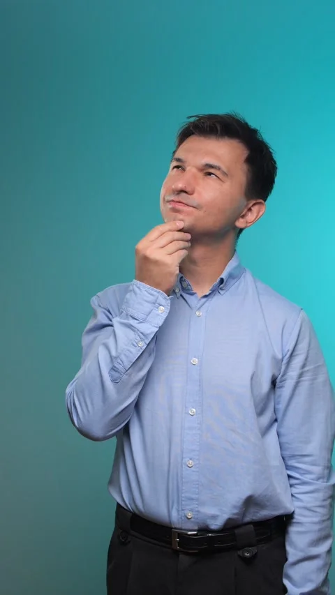 Vertical video young man standing and looking up thoughtfully, pondering a Stock Footage 342771888
