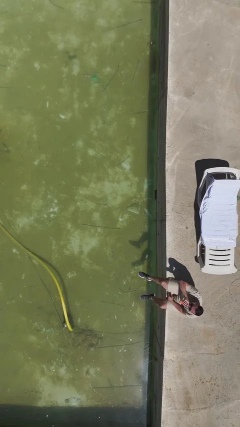 Vertical Video: A young man on a sun lounger relaxes near a dirty, half-finished Stock Footage 297663097