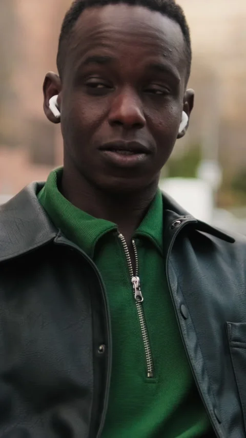 Vertical video, Young Man Talks on Earbuds on City Bench Stock Footage 327176798