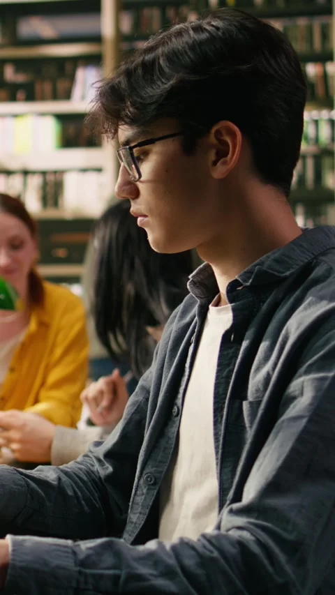 Vertical Video Young man typing on laptop in library study space and learning Stock Footage 336379528