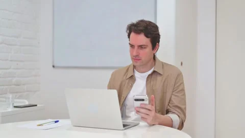 Vertical Video, Young Man Working on Phone and Laptop Video stock 312914360