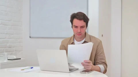 Vertical Video, Young Man Working on Laptop and Documents, Paperwork Stock Footage 312914373