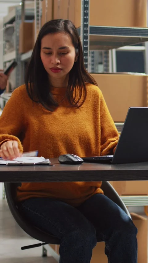 Vertical video: Young person doing stock inventory with laptop Stock Footage 232398365