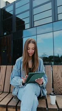 Vertical video. Young person using digital tablet on a sunny day. Freelance a Stock Photos