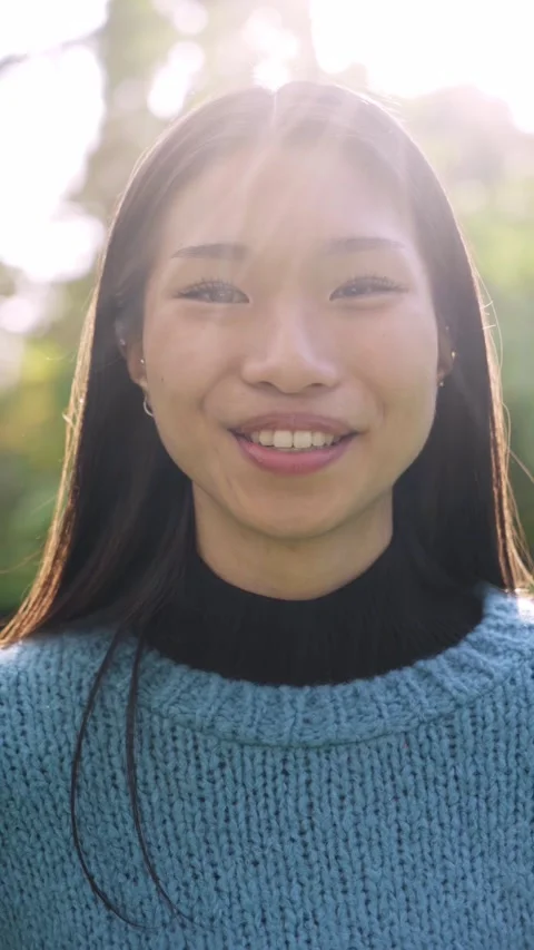 Vertical video of young pretty asian woman smiling and looking camera outdoors Stock Footage 221789720