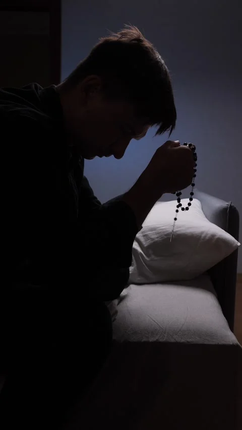 Vertical video Young priest praying with rosary in dark room Stock Footage 317253433