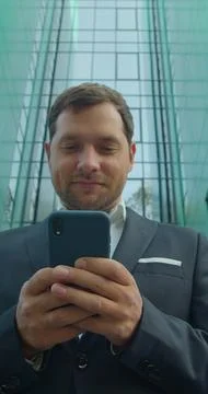 Vertical video. Young Professional Using Smartphone Near Business Center. Fotos Stock