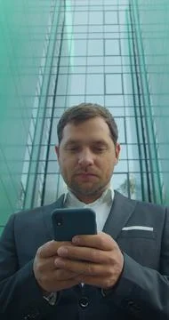 Vertical video. Young Professional Using Smartphone Near Business Center. Fotos Stock