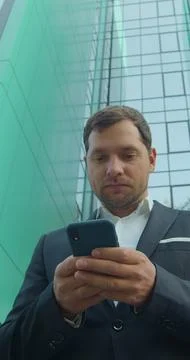 Vertical video. Young Professional Using Smartphone Near Business Center. Fotos Stock