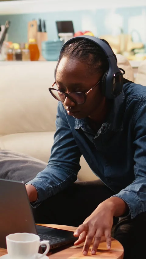 Vertical Video Young woman multitasking with music on headset and solving tasks Video stock 344529228