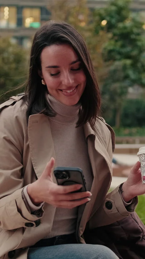 Vertical video, Young Woman Using Smartphone and Drinking Coffee Stock Footage 303777700