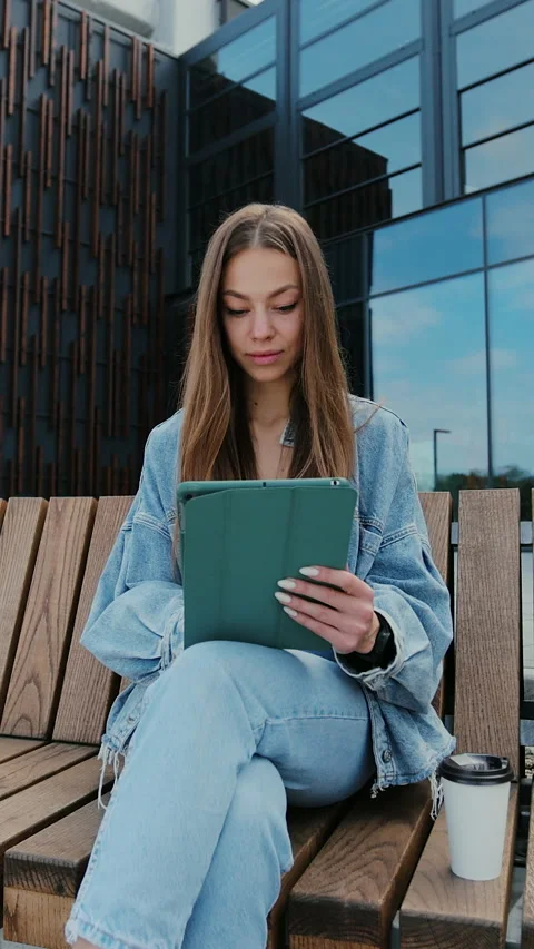 Vertical video. Young woman using tablet computer outdoors. Stock Footage 344683392