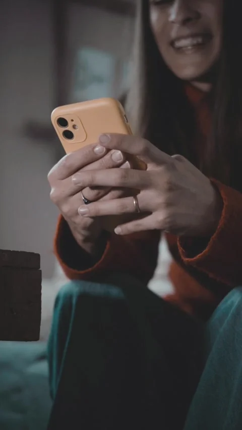 Vertical video of a young woman using her smartphone at night at home. Digital l Stock Footage 346323128