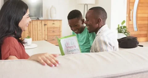 Vertical video: Youth in green tee offering Happy Fathers Day card, dad reading Stock Footage 337098341