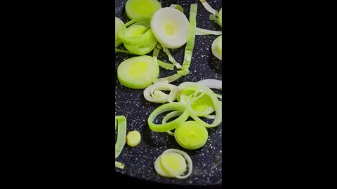 Vertical video.Chef frying leeks in a pan and stirring them with a spatula. Stock Footage 302636865