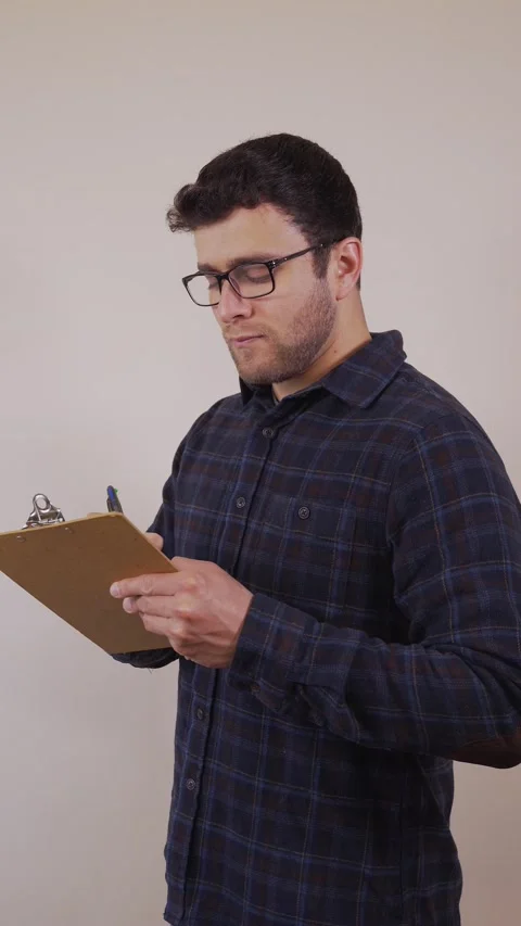 Vertical video.white man with glasses,writing down on a list of paper,thinkin Stock Footage 236678001