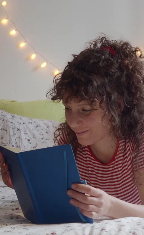 Vertical video.Woman lying in bed reading a book. Literature, novel, reading Stock Footage 207522154