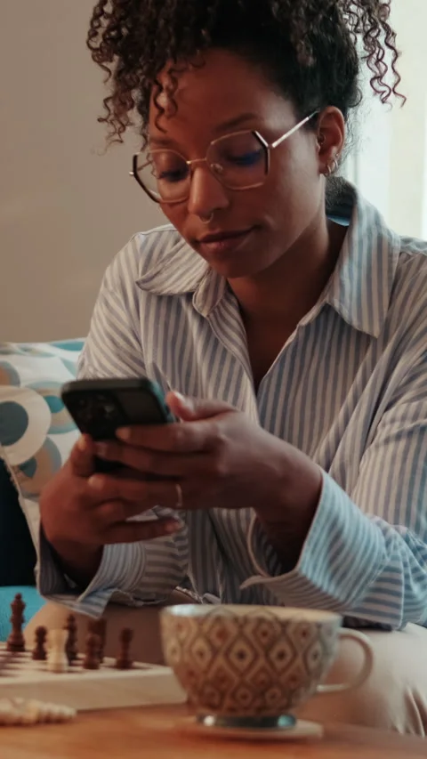 Vertical video,Woman on Sofa with Phone and Chessboard Stock Footage 317943995