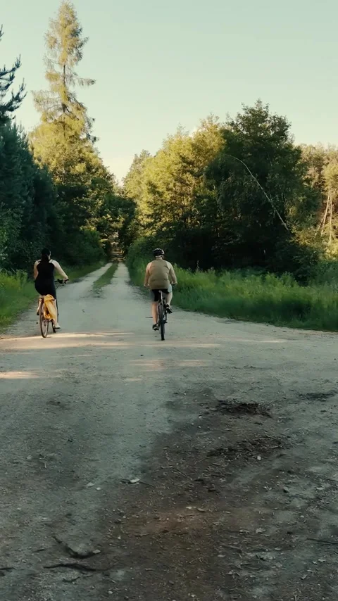 Vertical view. Active couple cycling on country dirt road during sunny day Stock Footage 348630682