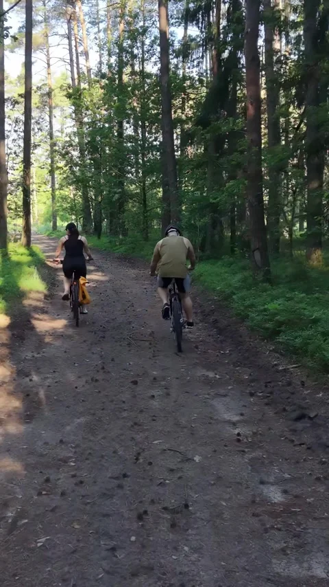 Vertical view. Active people riding bicycles on gravel path in green nature Stock Footage 348630700
