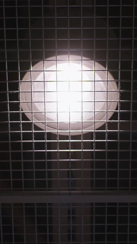 Vertical view of an airport ceiling light shining through a metal grid panel 库存影片 336224852