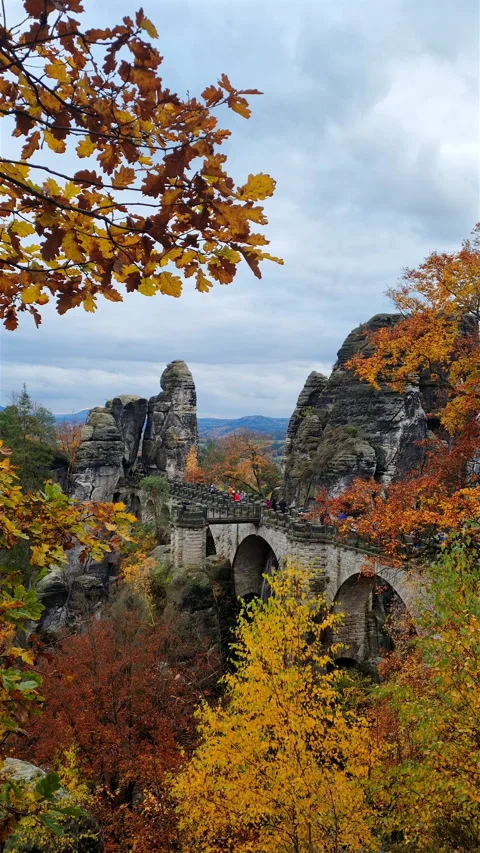 Vertical view of Bastei bridge framed by golden autumn oak leaves. Stock-Footage 345555017