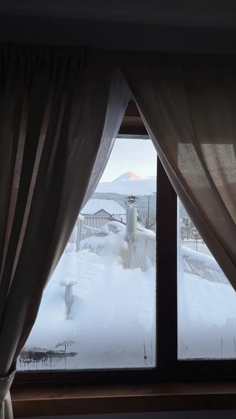 Vertical view from a bedroom window toward Llaima Volcano on a snowy dawn in 库存影片 348696125