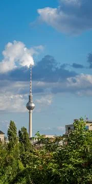 Vertical view of Berlin TV Tower (Fernsehturm) with foliage and rooftops, s.. Fotos de archivo