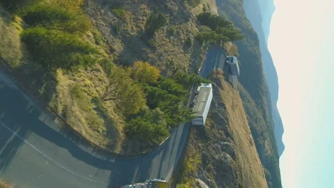 Vertical view of big trucks driving up a winding road through the Beklemeto in Stock Footage 232496219