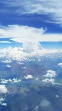 Vertical view of a blue sky with white fluffy cumulus clouds from an airplane Stock Photos