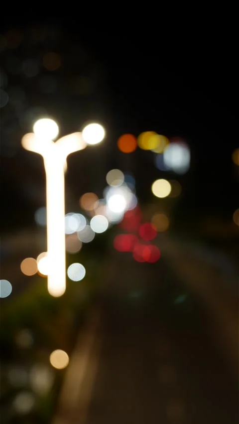 Vertical view of blurred traffic lights and street lamps forming colorful bokeh Vídeos de archivo 332723931