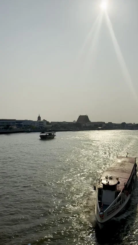Vertical View of Boat on Chao Phraya River with Wat Arun Silhouette Stock Footage 339044895