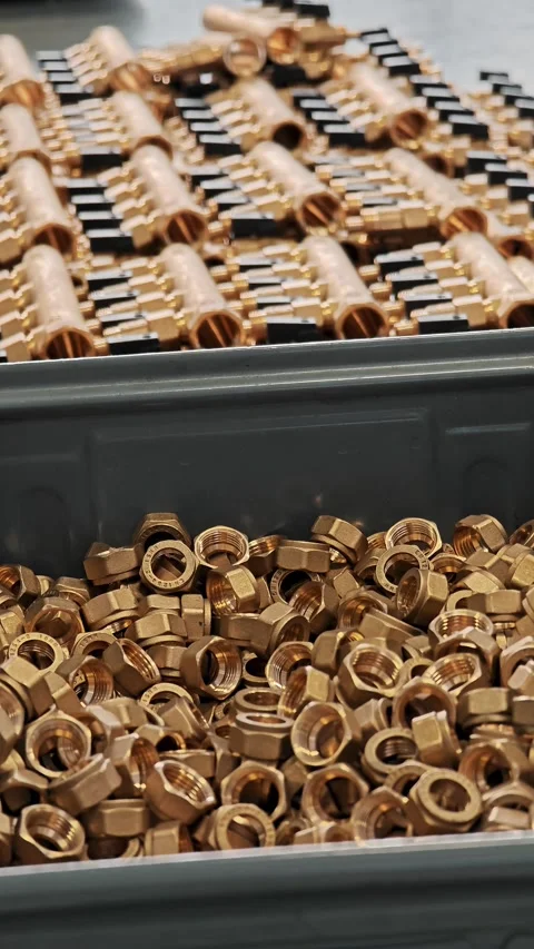 Vertical view of brass fittings in a bin with manifolds behind. Industrial Stock Footage 329327075