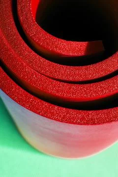 Vertical view of bright red rolled fitness foam mat for exercises Stock Photos