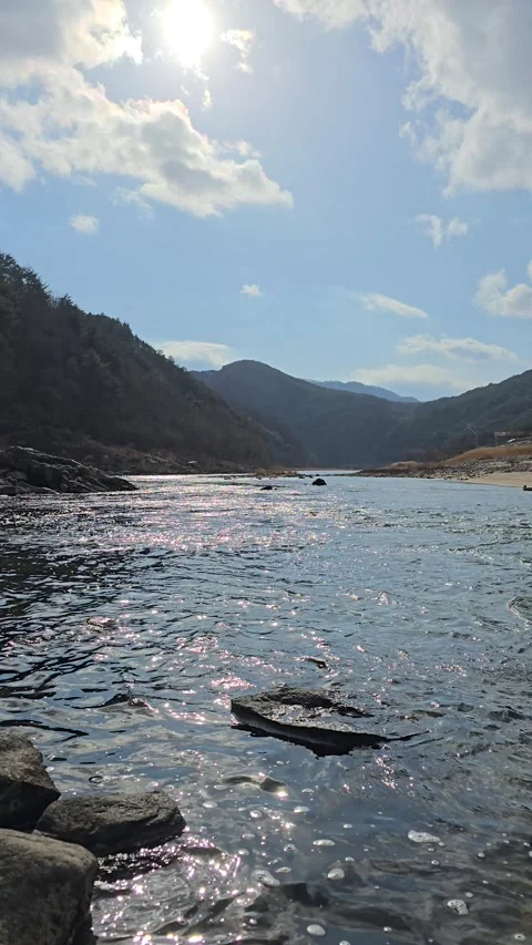Vertical View of Bright Sun and Blue Sky Over Glistening River in South Korea Stock Footage 330855387