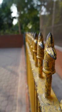 Vertical View of Bright Yellow Painted Iron Fence With Sharp Points Stock Photos