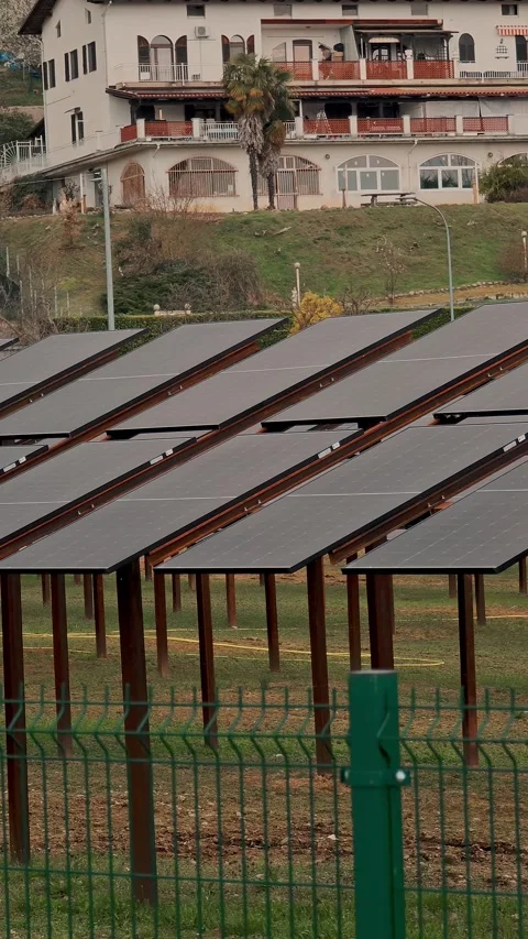 Vertical view of brown solar panels behind green fence, renewable energy near Stock Footage 330794781