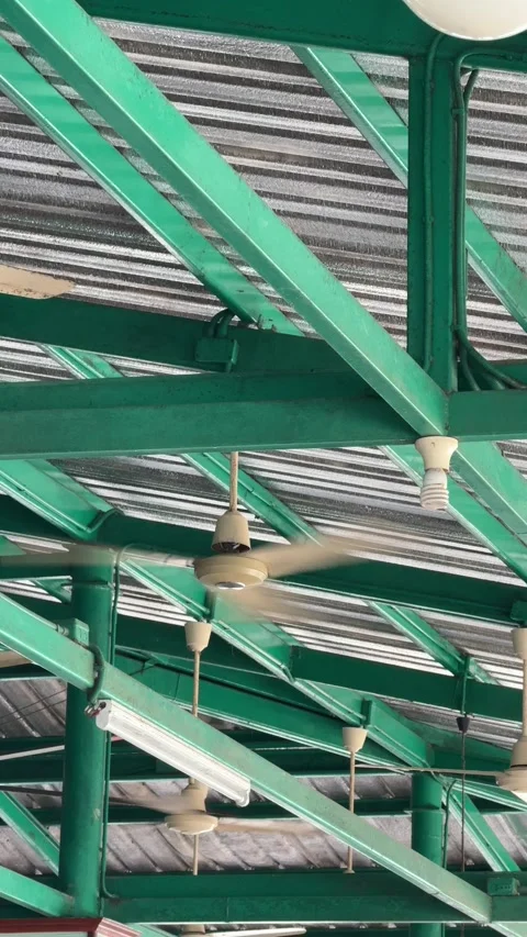Vertical View Of Ceiling Fans Spinning Under Green Steel Roof Truss In Cafeteria Stock Footage 345710570