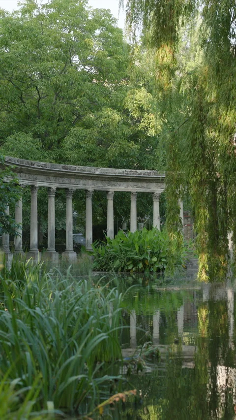 Vertical View of Classical Corinthian Colonnade Reflecting in a Serene Park Pond Stock Footage 340477456