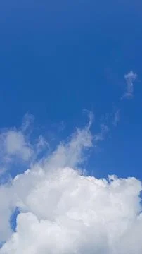 Vertical view of a clear blue sky with soft white clouds creating a bright Foto stock