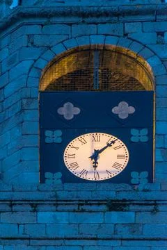 Vertical view of a clock in an illuminated stone tower at night, marking six  Stock Photos