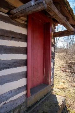 Vertical view of colonial log cabin red door Stock Photos