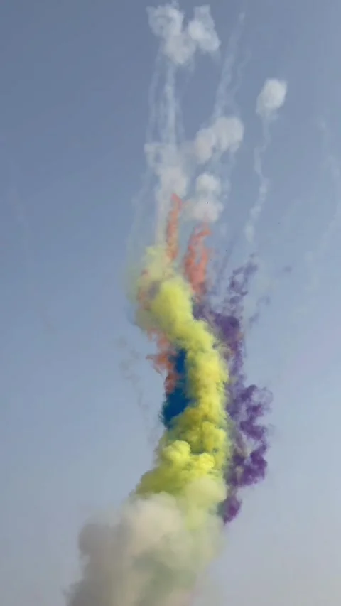 Vertical view of colorful Holi smoke bombs and daytime fireworks in blue sky Stock Footage 342996481