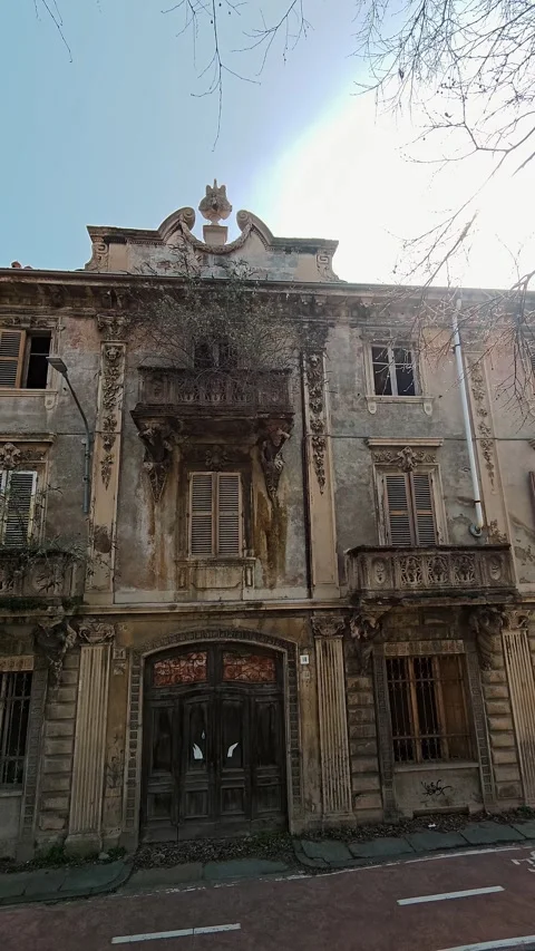 Vertical view of a decaying urban building with trees on balconies, sun glare Stock Footage 330794431