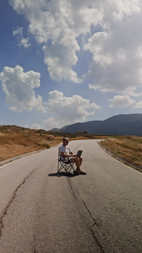 Vertical View of Digital Nomad Working on Laptop on Empty Mountain Road Vídeos de archivo 346547272