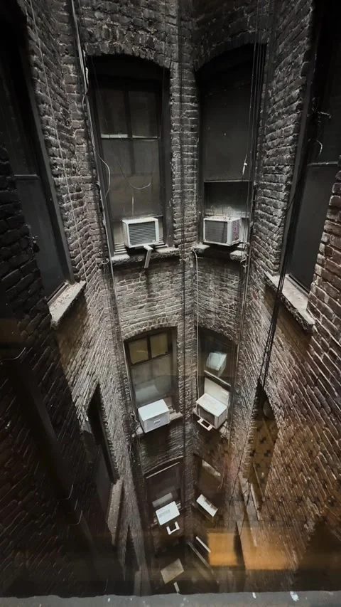 Vertical View Down Brick Air Shaft with Windows and Air Conditioners in Vídeo Stock 340571941