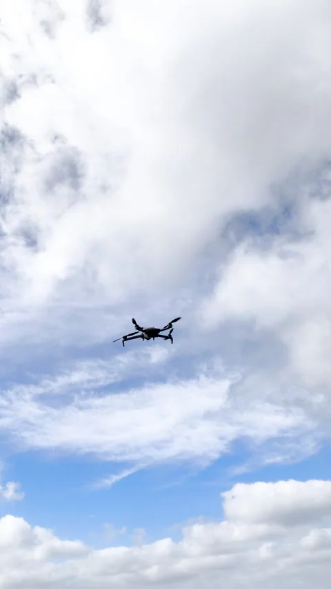 Vertical view of drone hovering under a cloudy sky Stock Footage 337717933